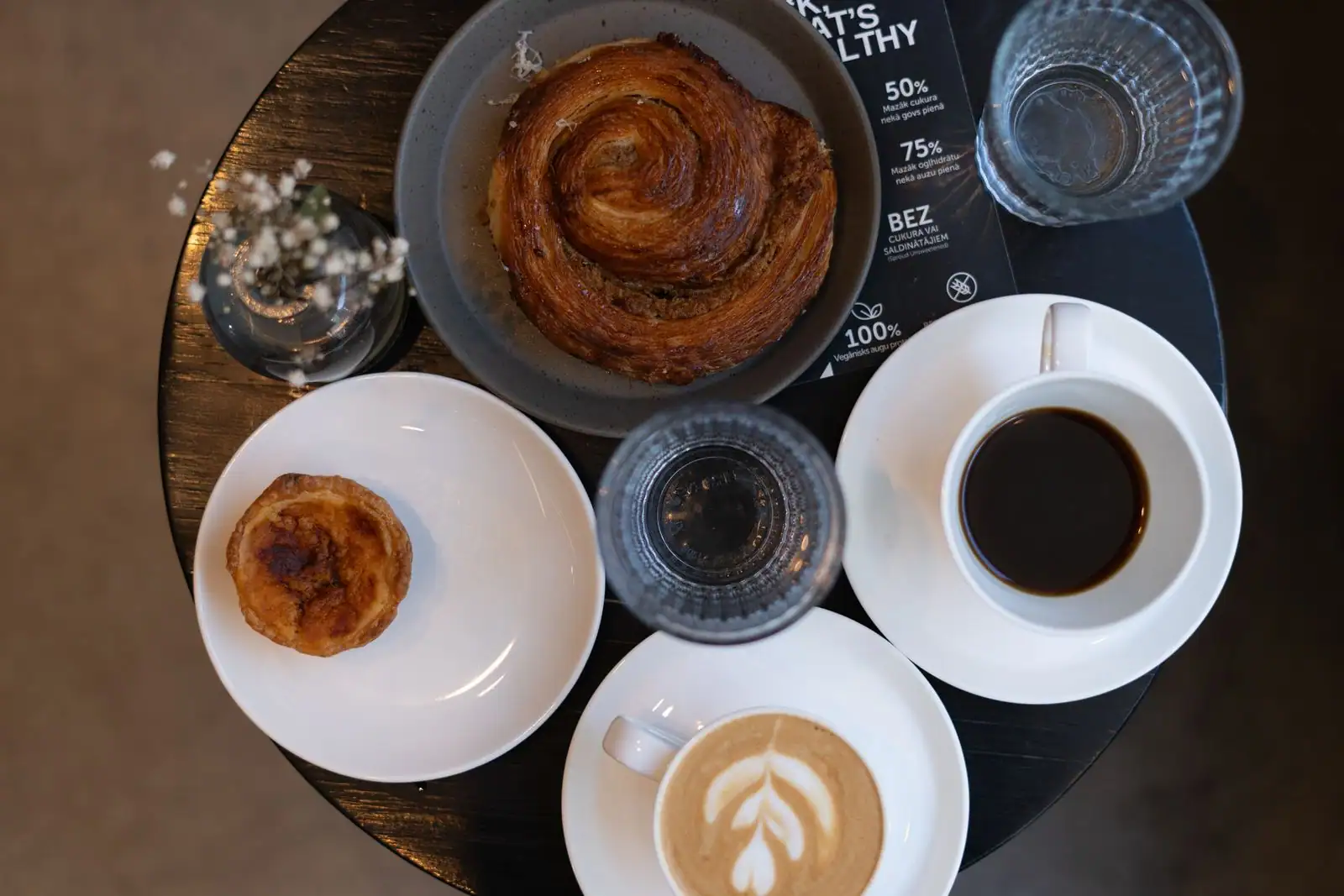 Deux cafés et des pâtisseries vus de dessus sur une table de café, dont un latte au dessin soigné.