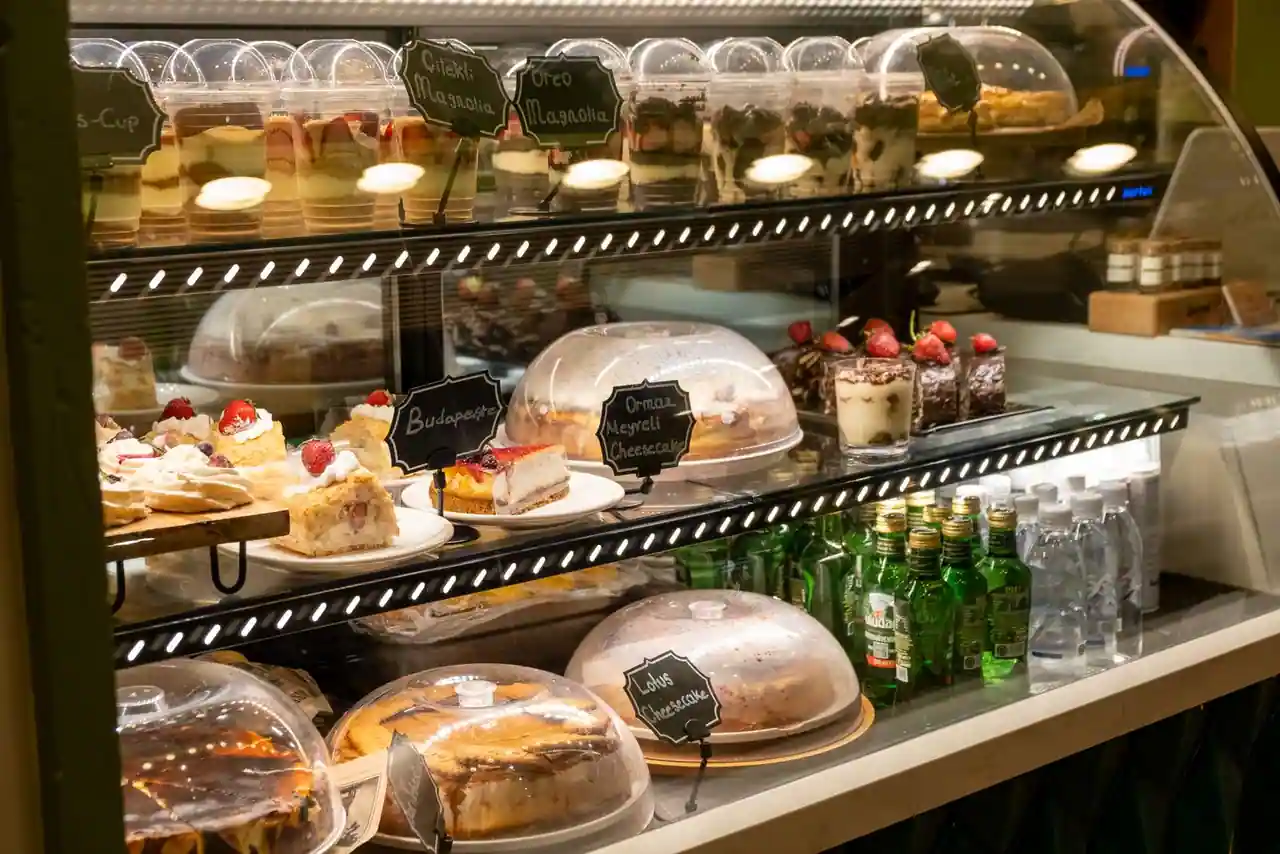 Vitrine de pâtisserie garnie de desserts variés et colorés présentés sur plusieurs niveaux.