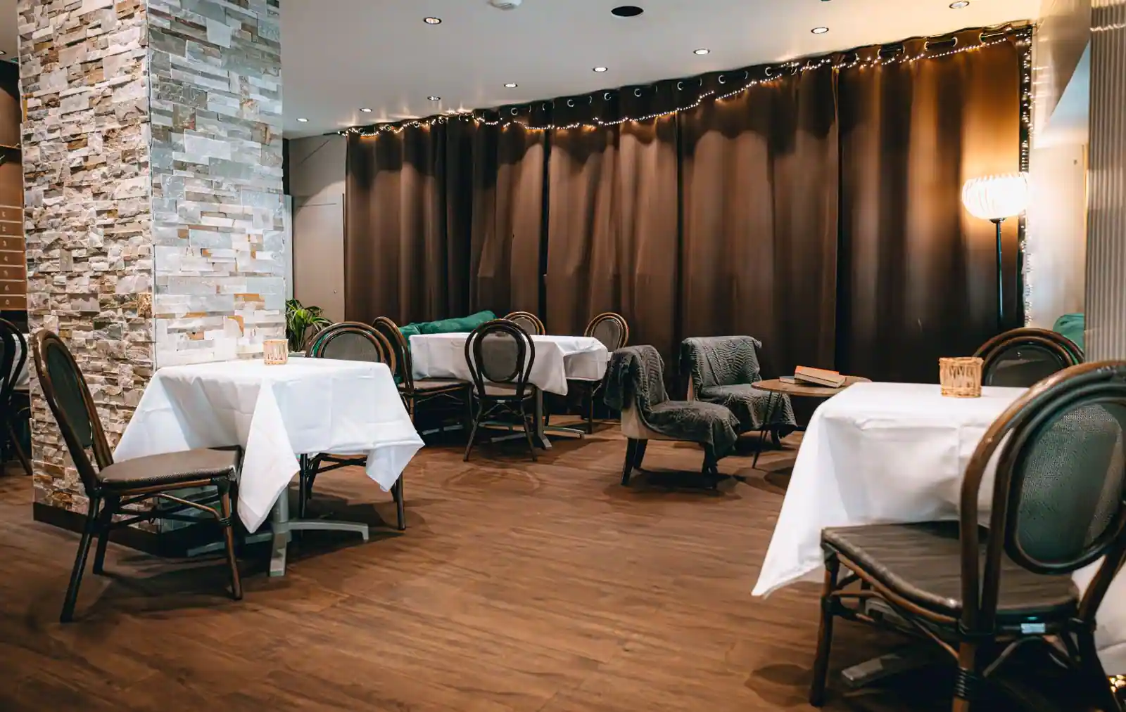 Salle de restaurant aux tables nappées de blanc et chaises bistrot, dans une ambiance chaleureuse.
