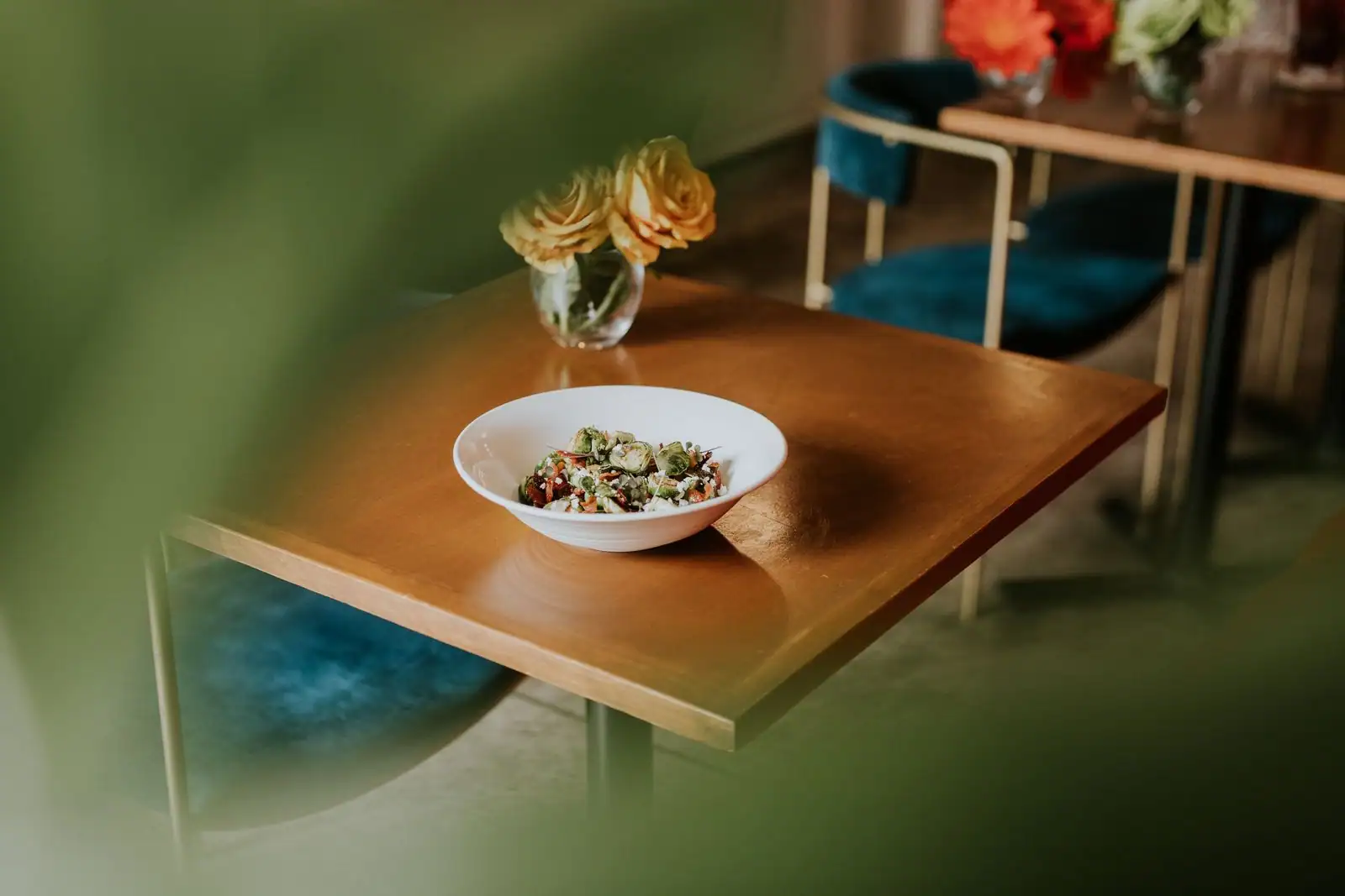 Bol de salade fraîche servi sur une table en bois, dans un café à l'ambiance chaleureuse.