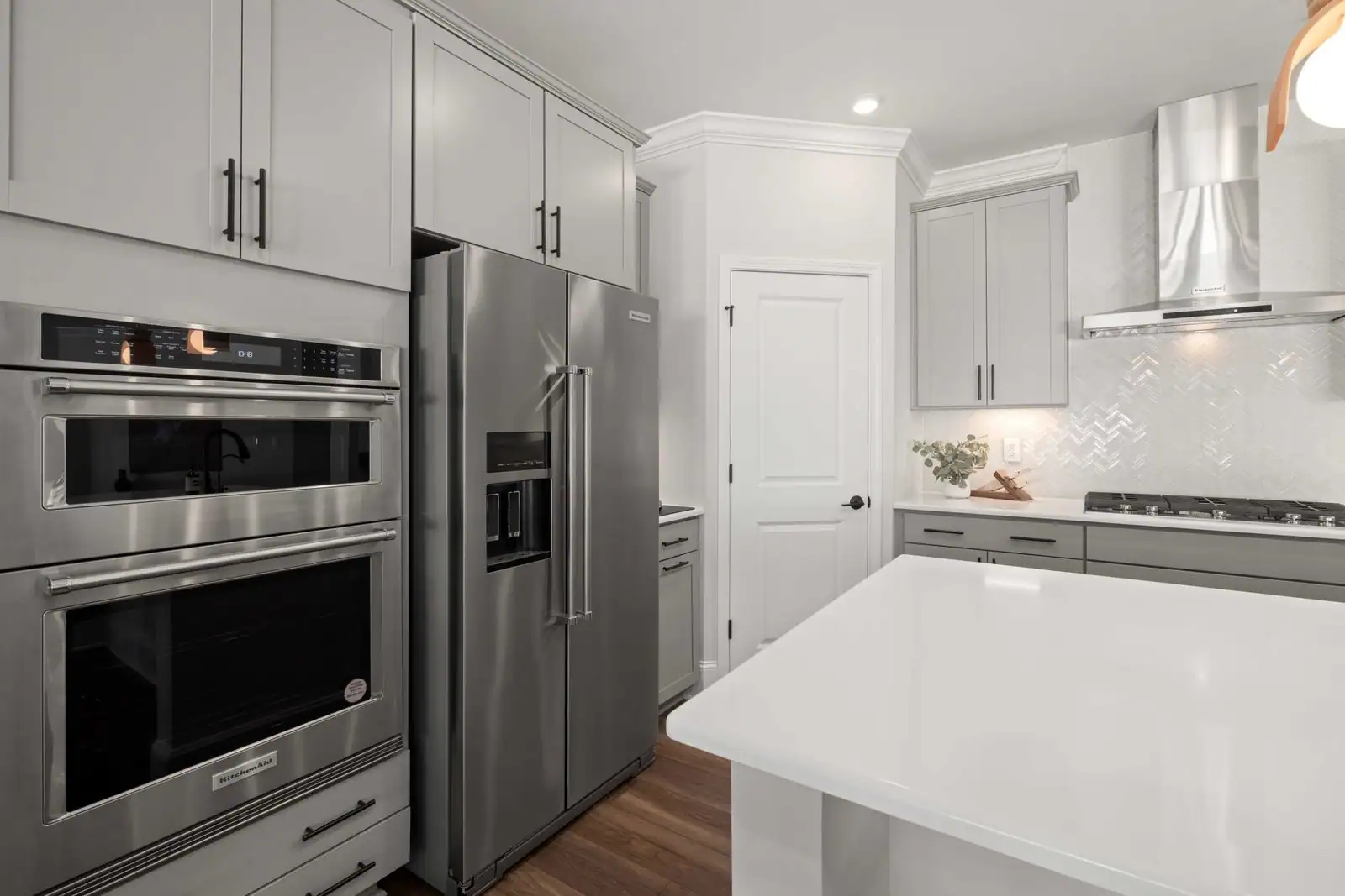 Cuisine moderne équipée d'électroménager en inox : four encastré, réfrigérateur, plaque et hotte.