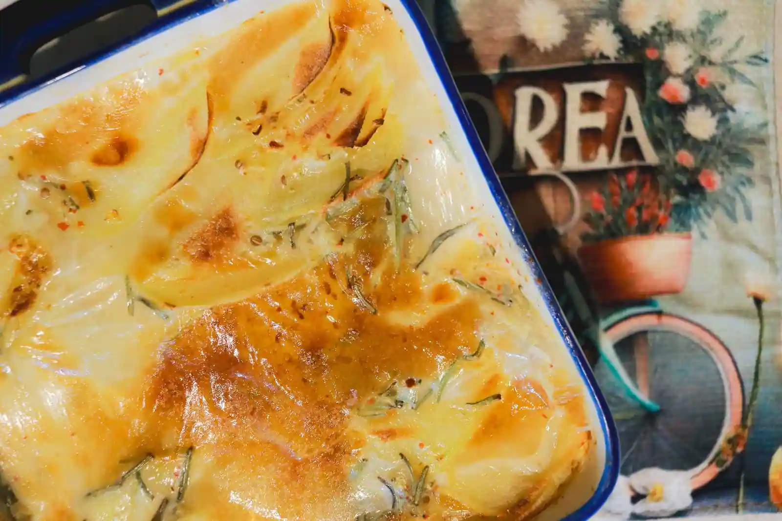 Gratin de légumes doré et gratiné dans un plat en céramique, posé sur un plan de travail.