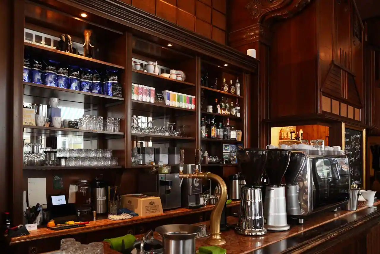 Comptoir en bois d'un coffee shop avec sa machine à espresso, ses verres et ses étagères garnies.