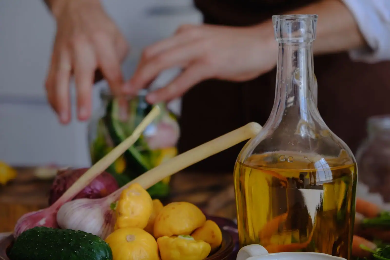 Bouteille d'huile d'olive et légumes frais, courges, ail et oignons, sur un plan de travail de cuisine.