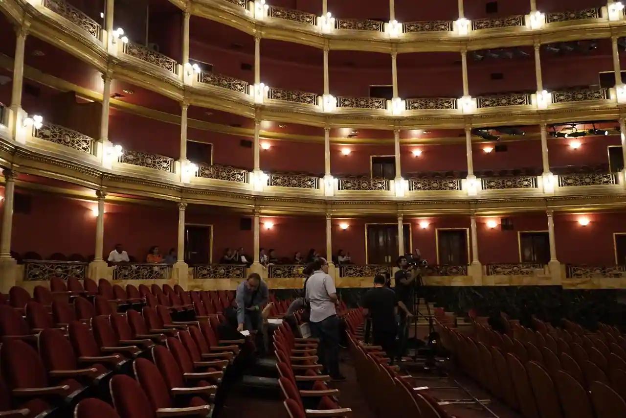 Intérieur d'une salle de théâtre à l'italienne, fauteuils de velours rouge et balcons dorés.