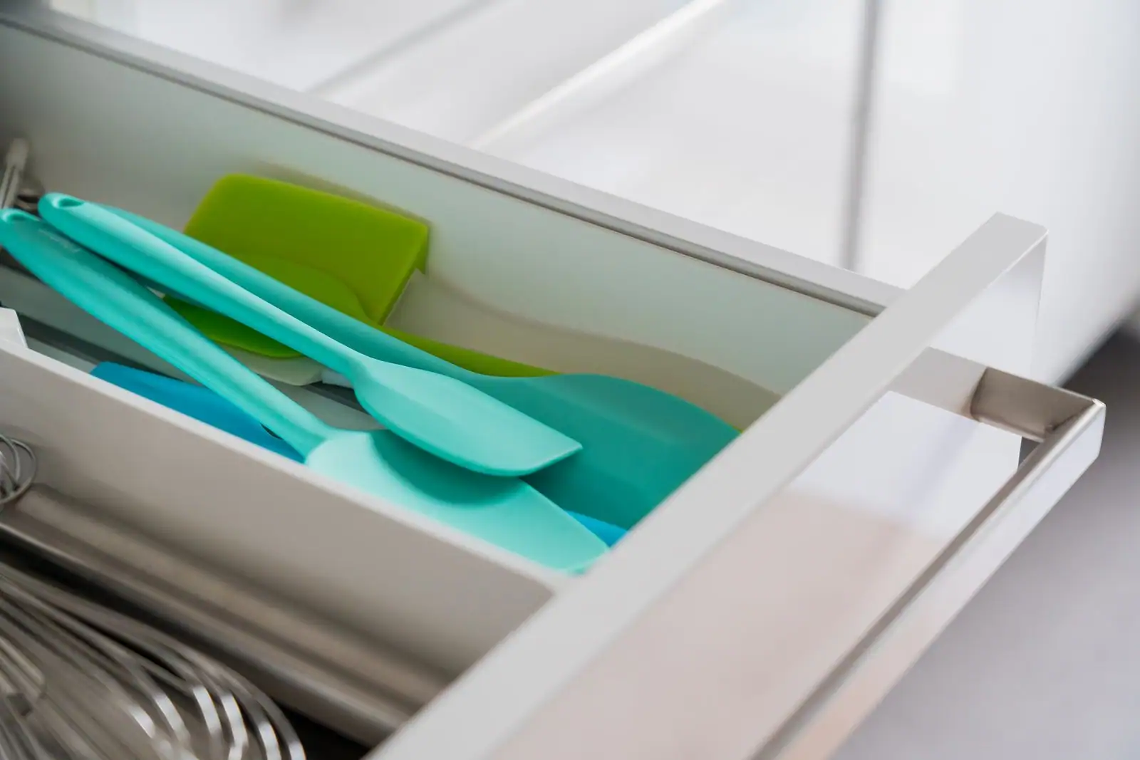 Spatules et maryses en silicone colorées rangées dans un tiroir de cuisine.