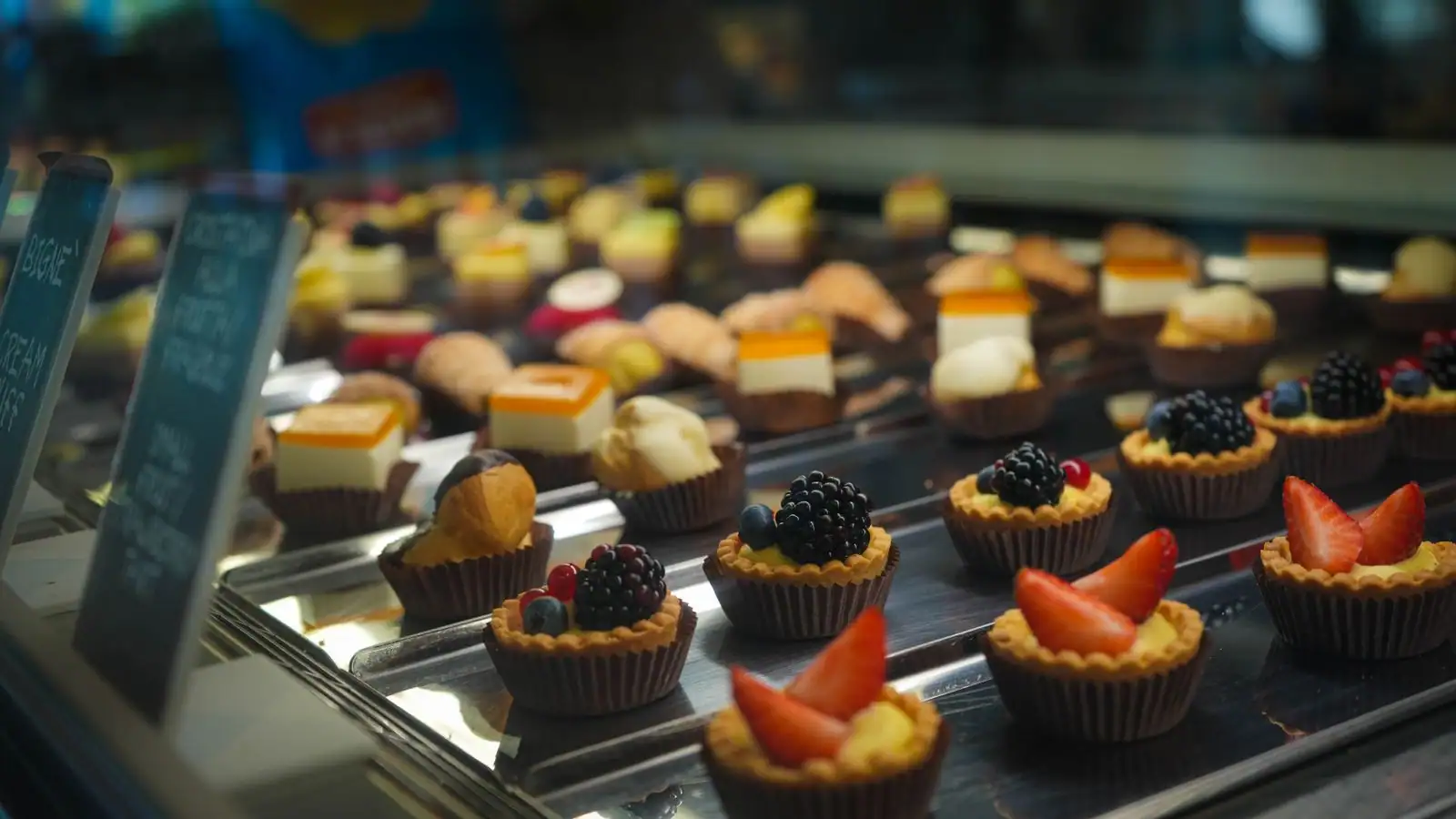 Vitrine réfrigérée de boulangerie garnie de tartelettes aux fruits et de petits gâteaux individuels
