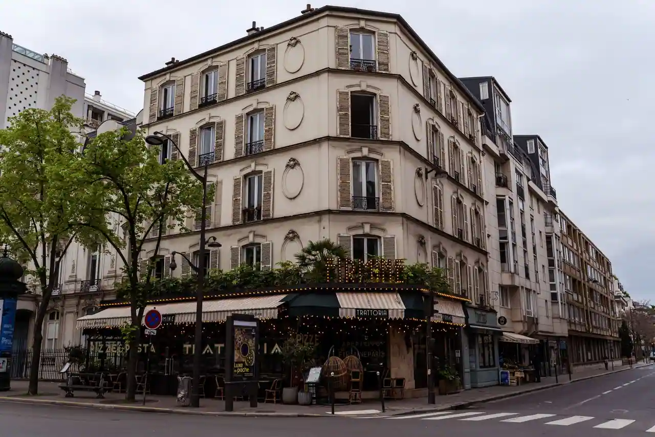 Café d'angle parisien avec sa terrasse et ses stores, dans un immeuble ancien, image illustrative.