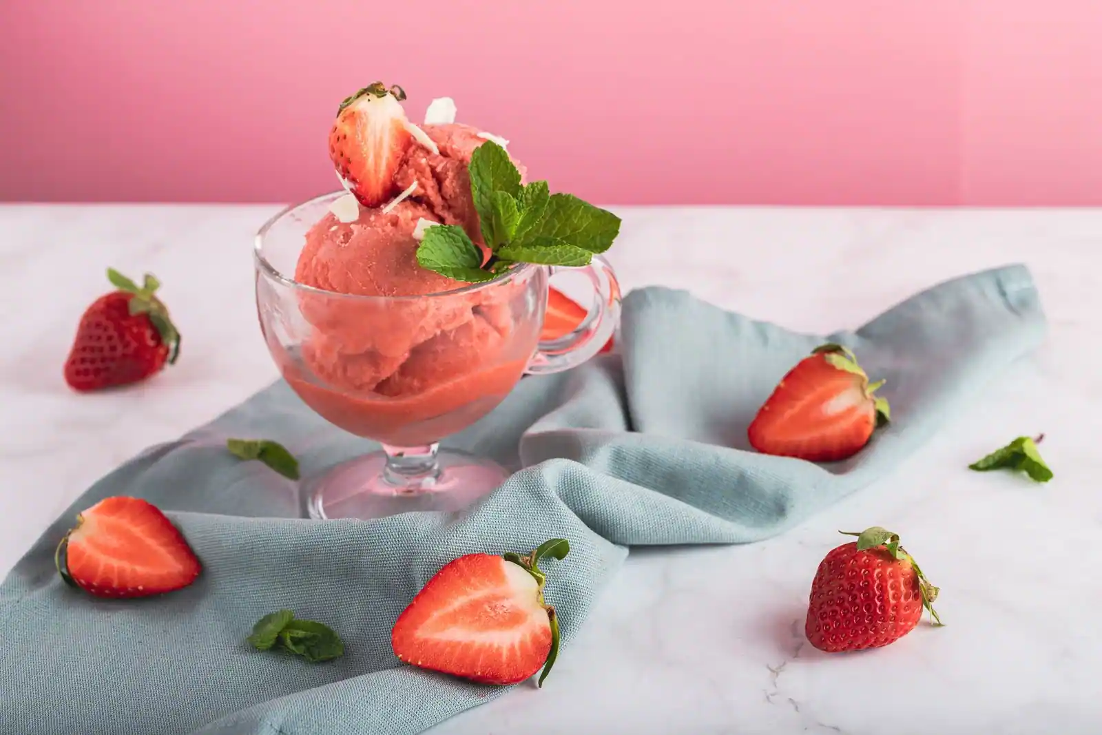 Coupe de glace aux fraises garnie de fraises fraîches et de feuilles de menthe.