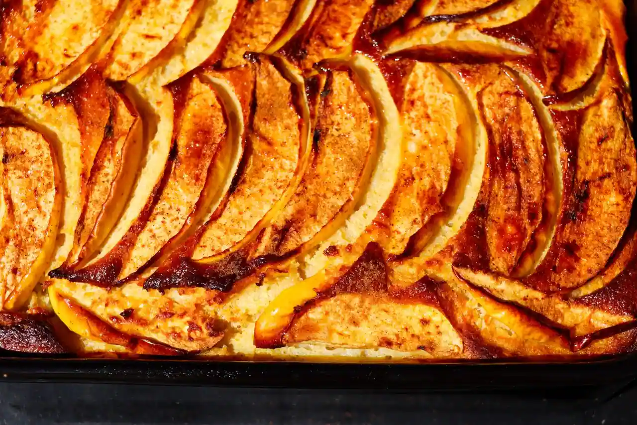 Gâteau moelleux aux pommes, fines lamelles caramélisées et dorées au four dans un plat