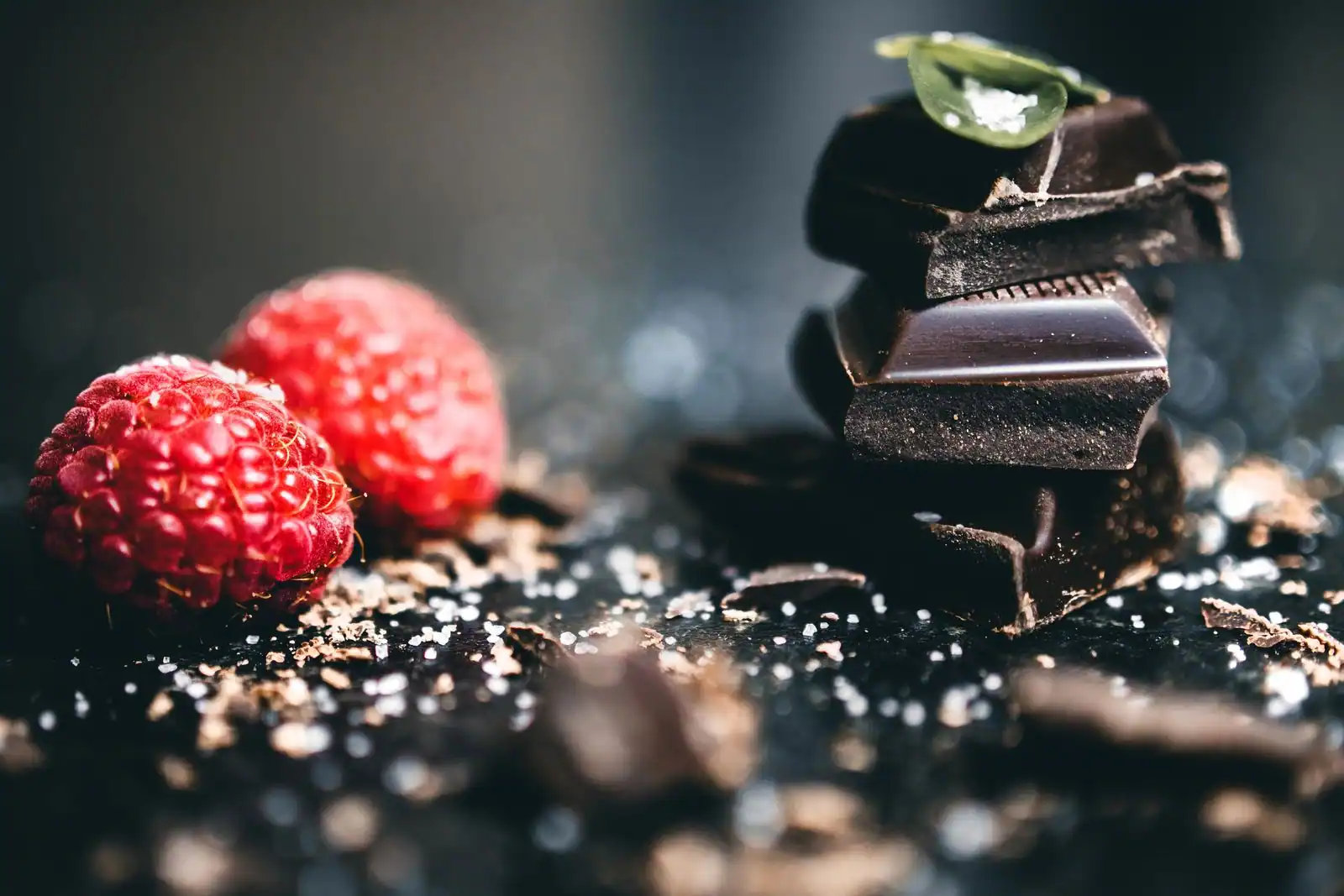Chocolat noir en morceaux et framboises fraîches, ingrédients d'un dessert vegan.