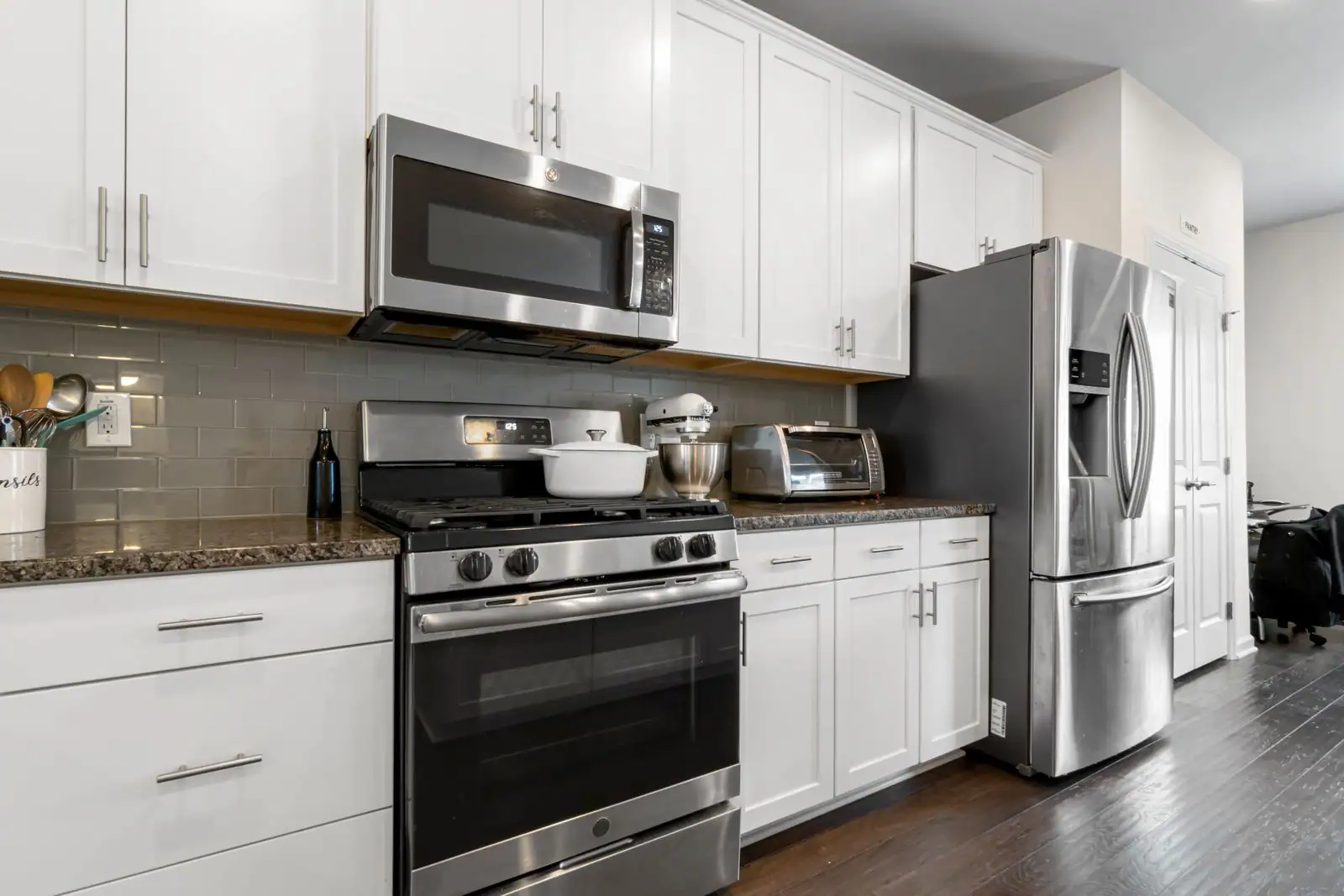Cuisine équipée moderne avec réfrigérateur, four et plaques de cuisson en acier inoxydable