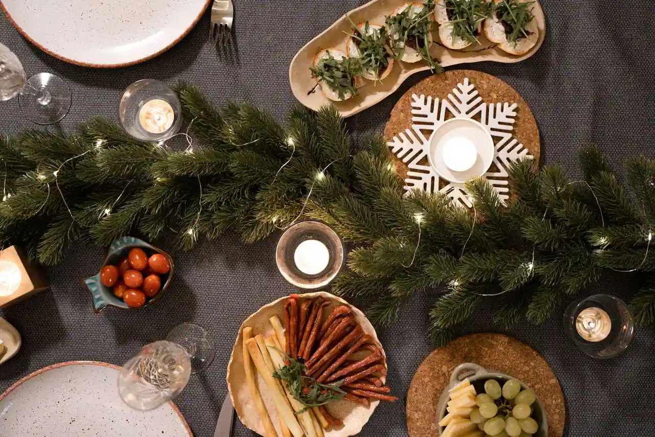 Table de Noël dressée avec des bougies et de la verdure, dans une ambiance élégante et chaleureuse.