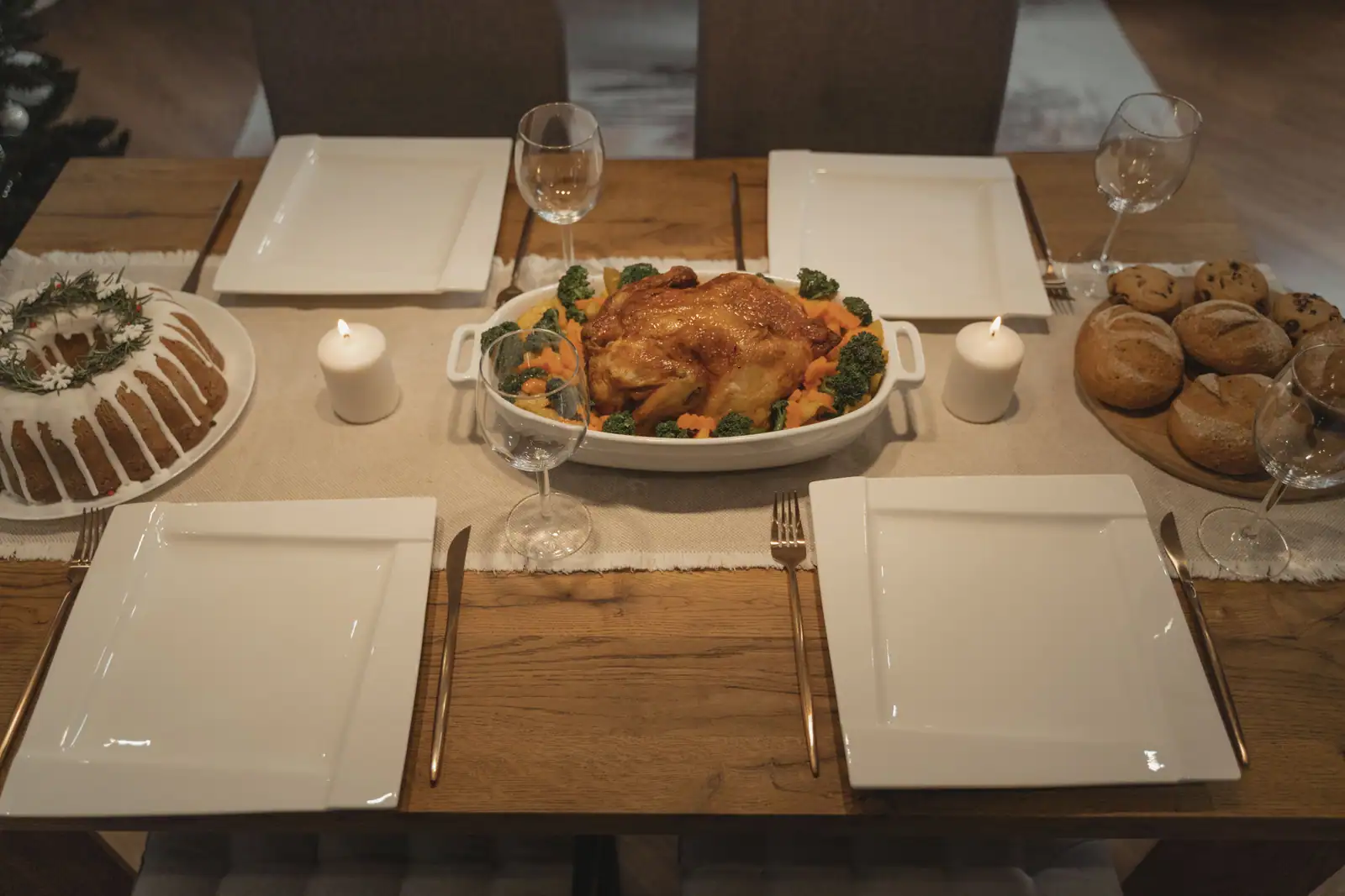 Table dressée pour un repas de fête, volaille rôtie au centre, gâteau et petits pains de chaque côté