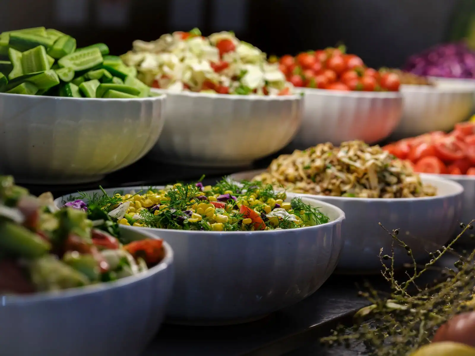 Assortiment de saladiers de légumes frais et colorés disposés pour un repas à partager.