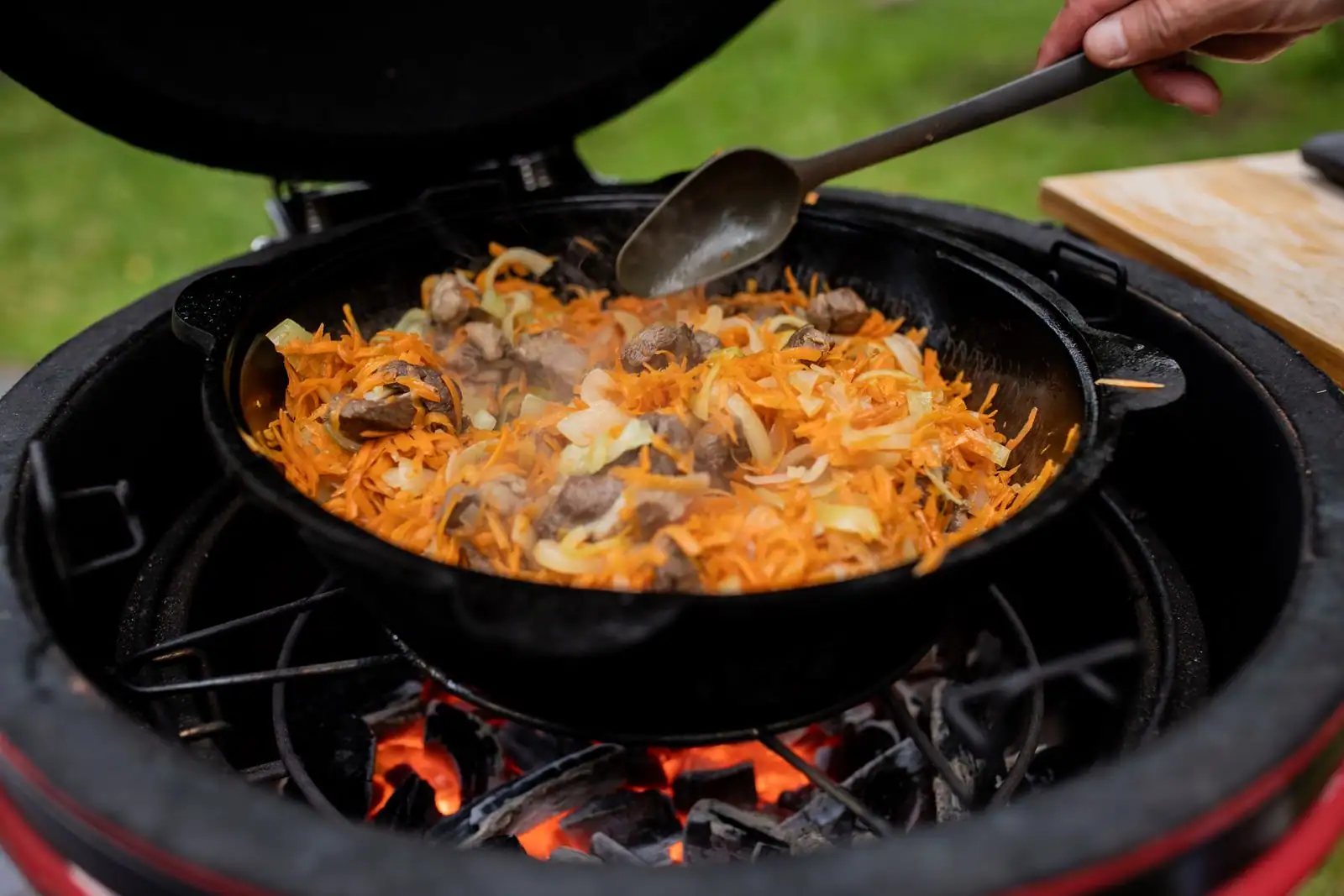 Plat mijoté de viande et de légumes cuisant dans une cocotte en fonte au-dessus d'un feu de braises.