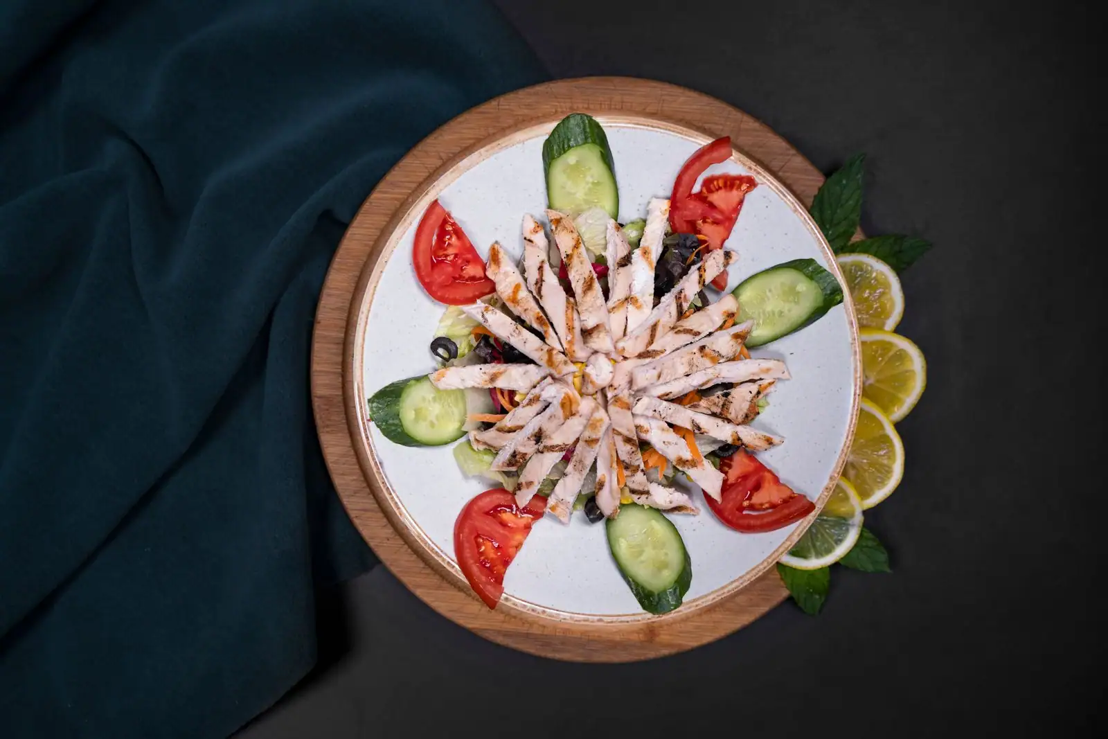 Assiette légère de poulet grillé accompagné de tomates, concombre et citron.