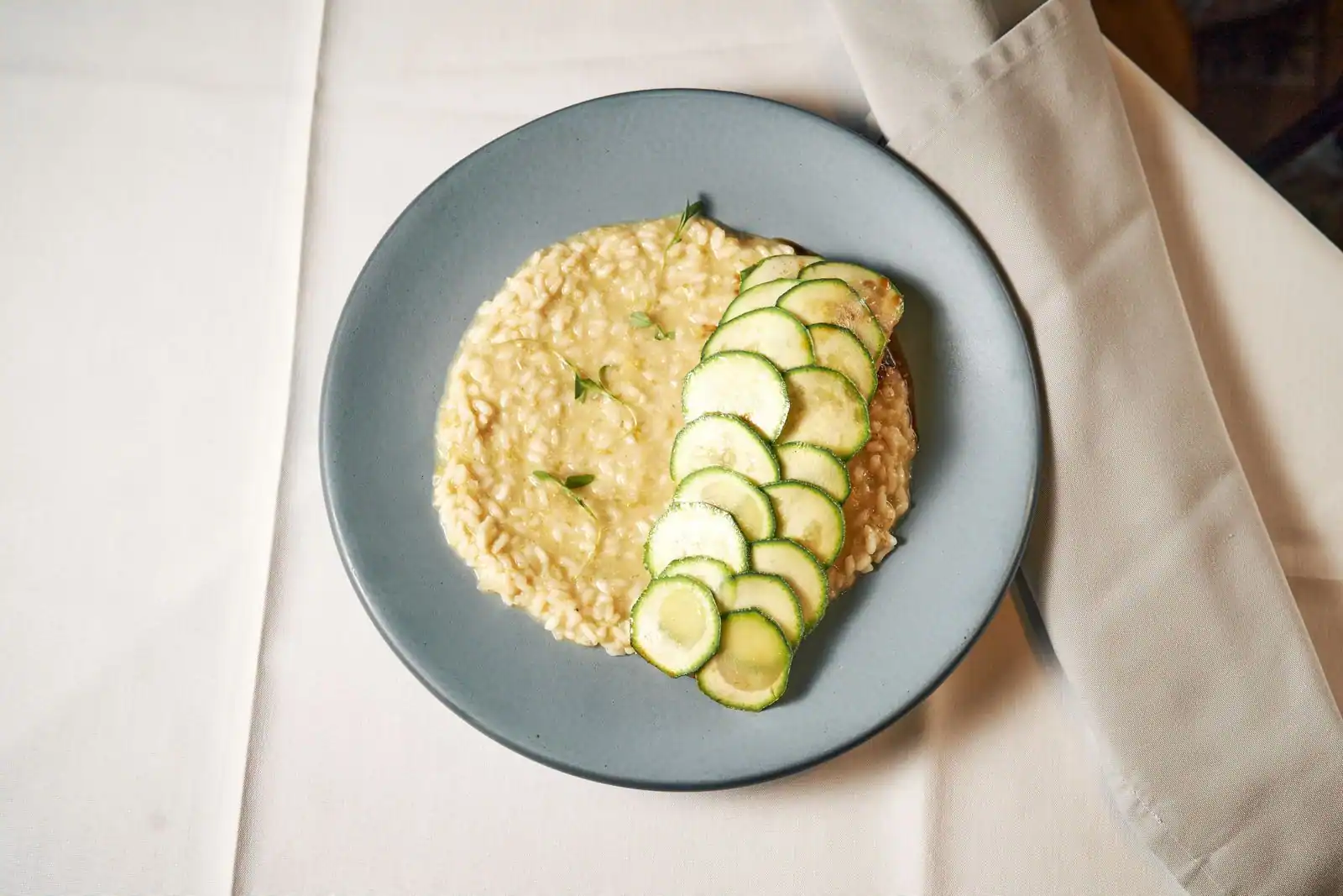 Assiette de risotto crémeux garni de fines lamelles de courgette, image d'illustration du plat.