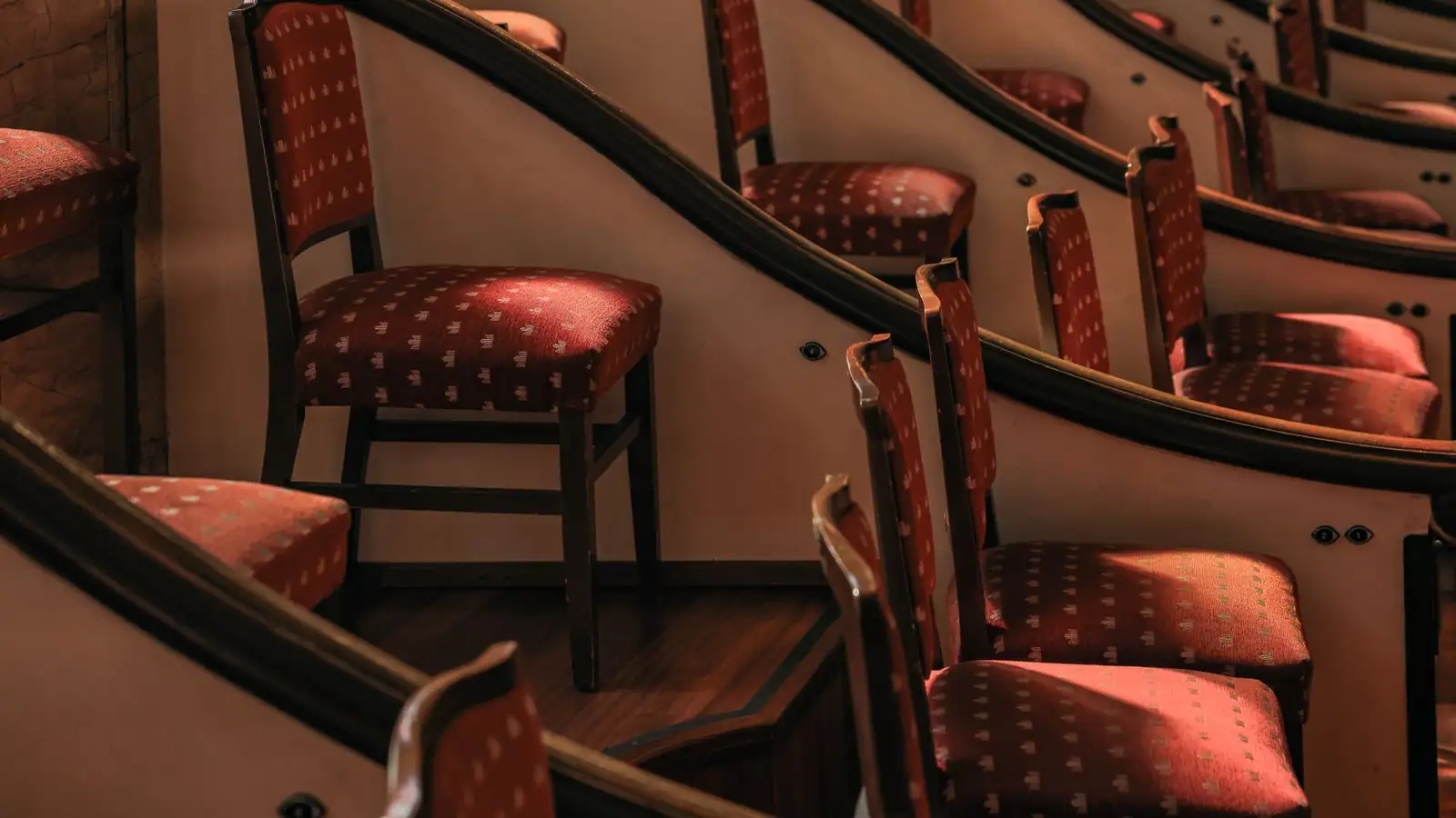 Rangées courbes de fauteuils de velours rouge dans la salle d'un théâtre à l'italienne