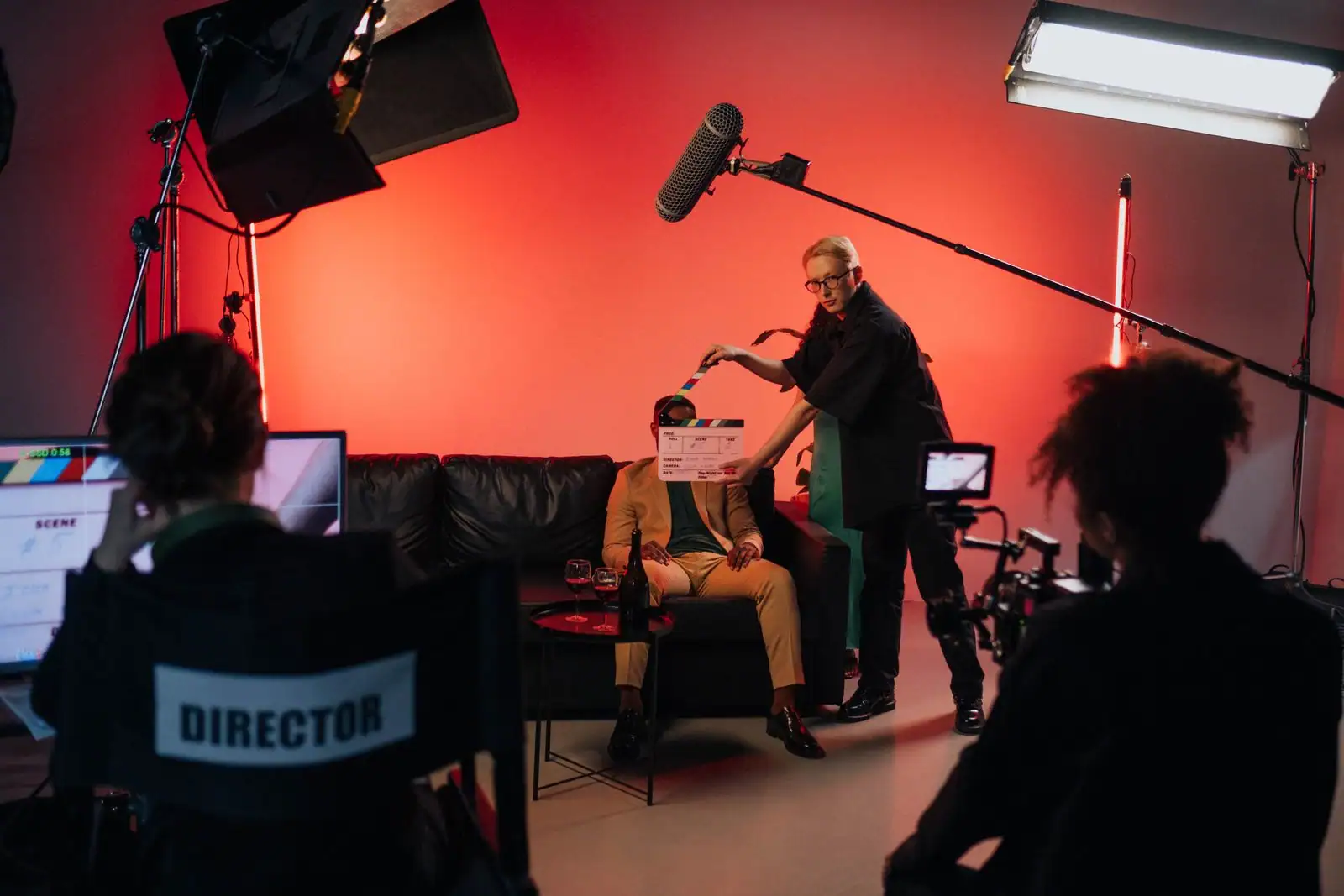 Comédien assis sur un plateau de tournage éclairé pendant qu'un technicien présente le clap devant lui