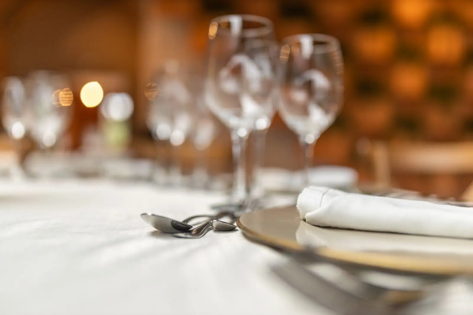 Table dressée avec assiettes, verres et couverts disposés avec soin sur une nappe claire