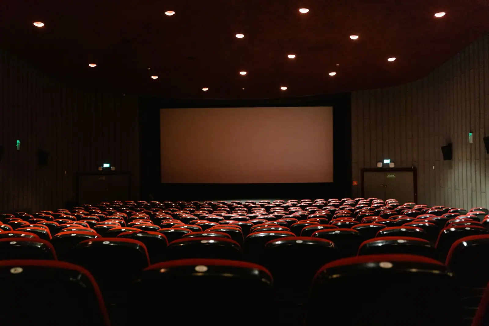 Salle de cinéma aux fauteuils rouges face au grand écran, image illustrant l'univers du cinéma.