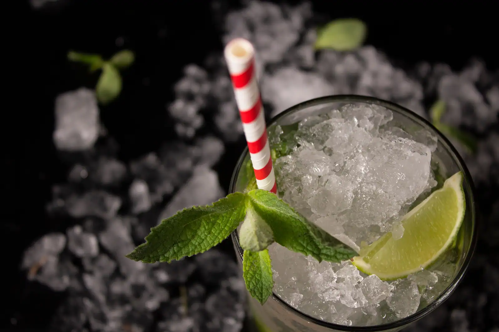 Verre haut rempli de glace pilée, feuilles de menthe entières et quartier de citron vert, vu de dessus