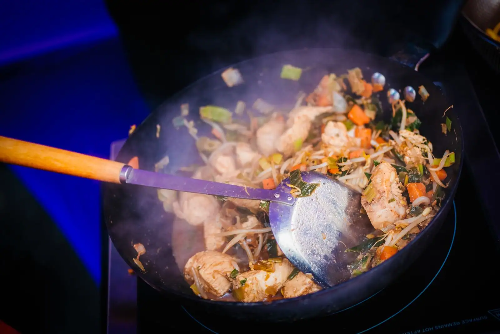 Cuisson au wok à feu vif : poulet et légumes sautés dans un grand wok, comme au restaurant minute.