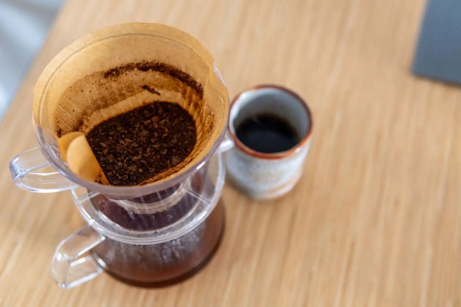 Tasse de café filtre posée sur une table en bois près d'un livre ouvert