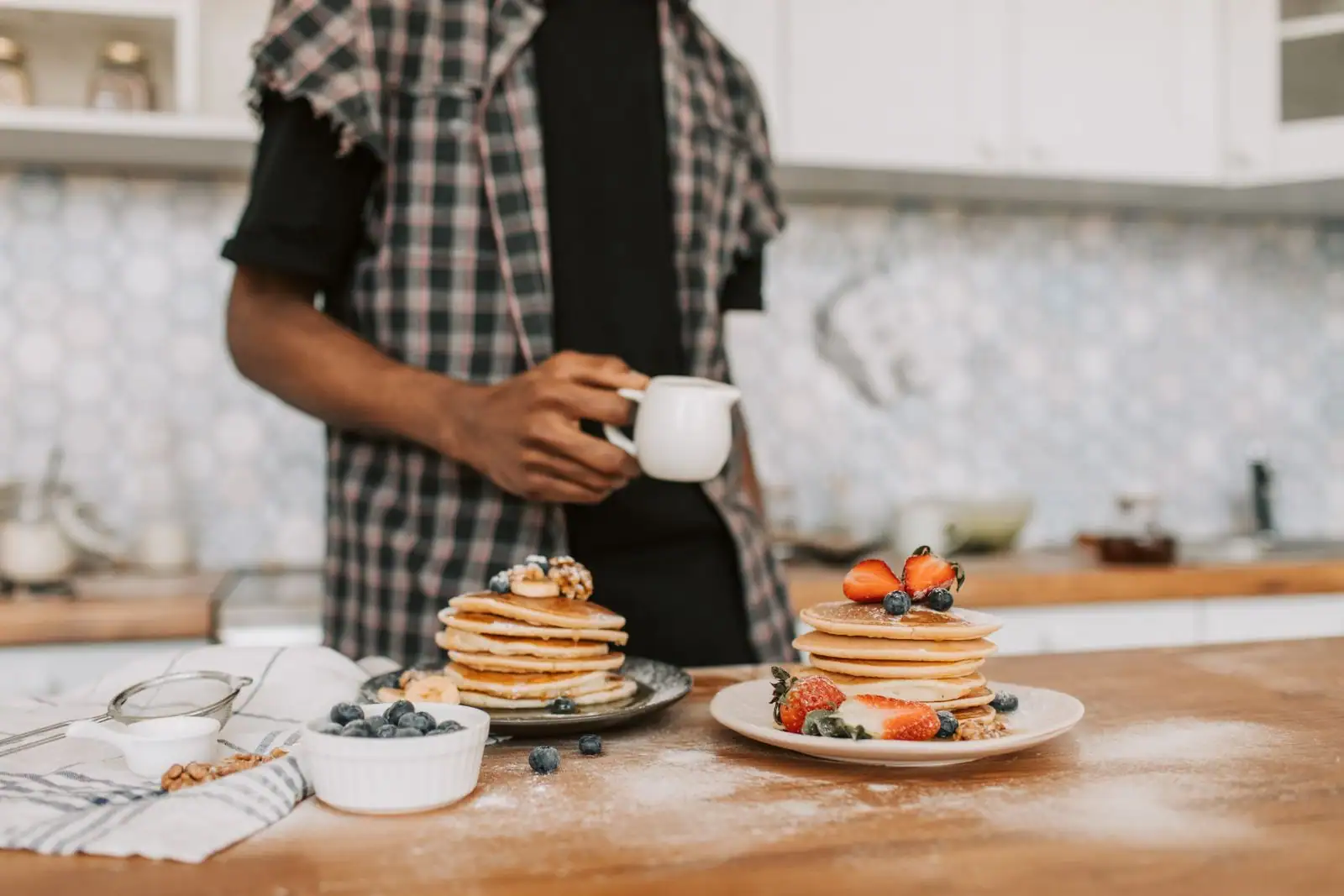 Pancakes dorés empilés sur une assiette avec farine et grains sur une table en bois