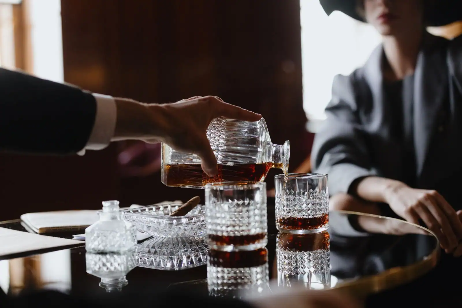 Verre de spiritueux ambré tenu à la lumière, dégustation sans étiquette de marque visible