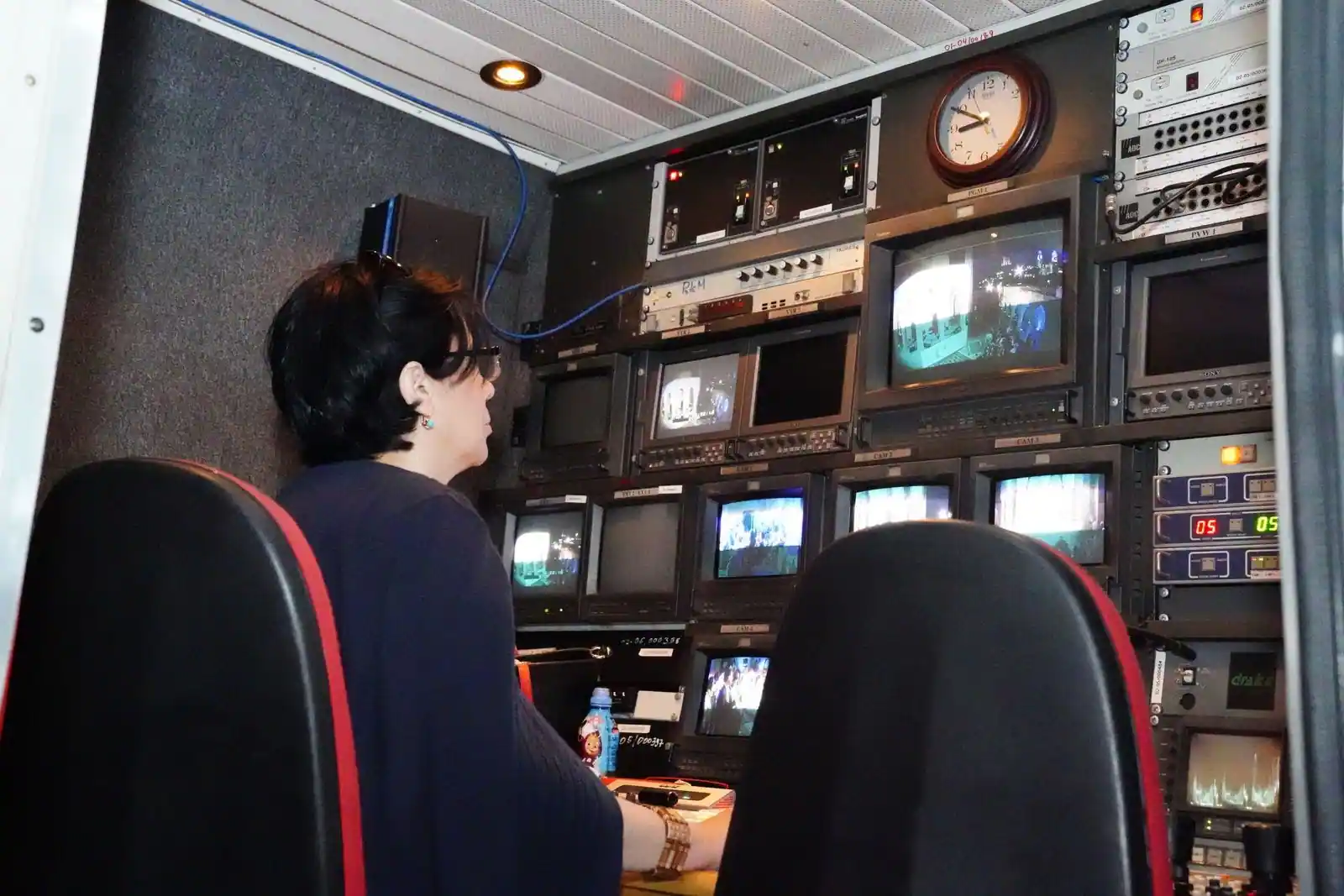 Journaliste dans un studio de télévision, écrans d'actualité internationale en arrière-plan