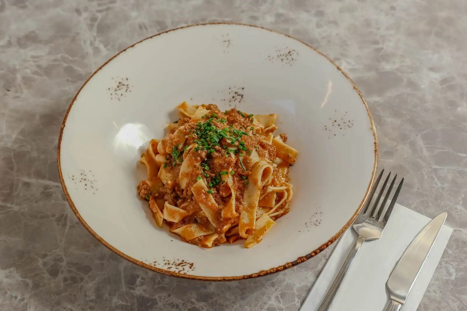 Tagliatelles fraîches nappées de ragù bolognaise, sauce viande-tomate mijotée, servies en assiette.